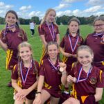 Old Vicarage School girls in their claret and gold sports kit with medal